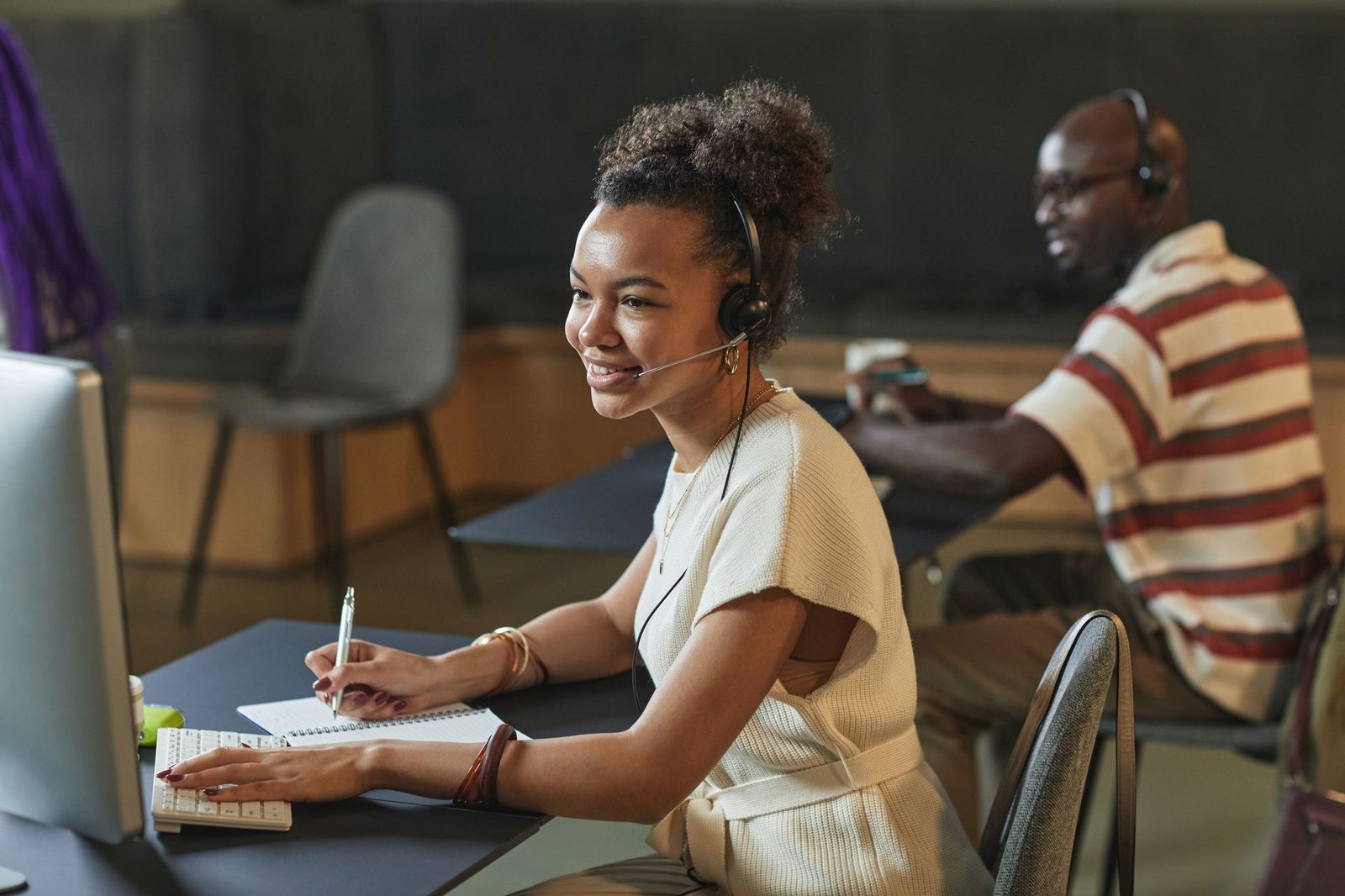 Atendente sorridente trabalhando com headset e computador
