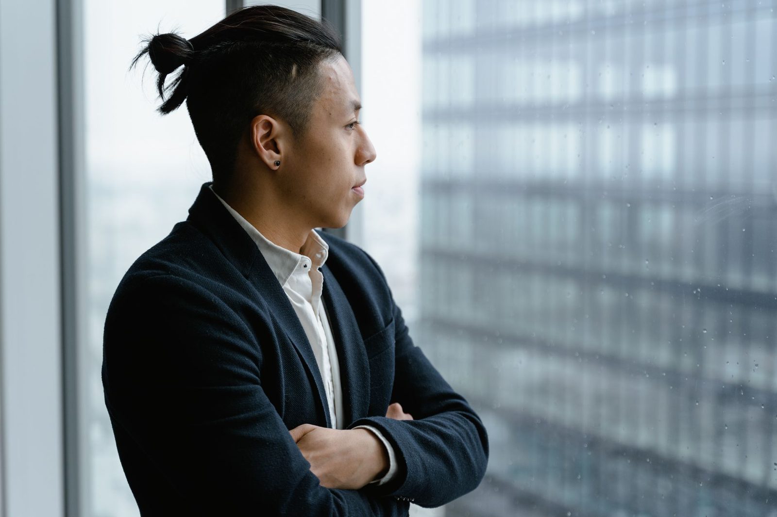 Empresário pensativo observando o horizonte pela janela do escritório, refletindo sobre o futuro dos negócios