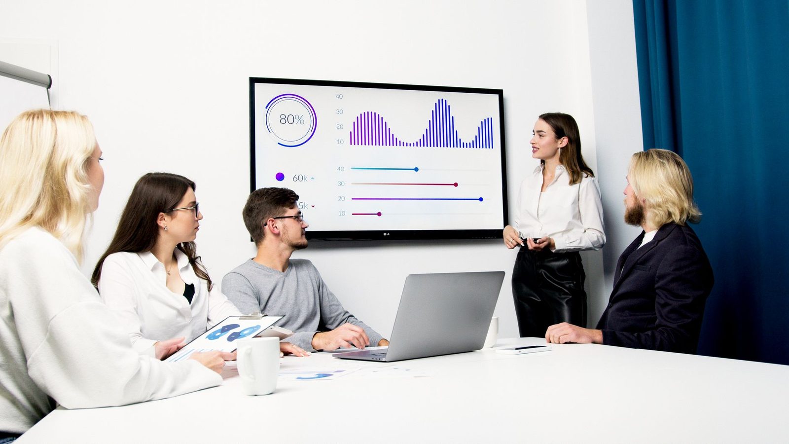 Equipe analisando dados de campanhas em uma tela durante reunião de negócios