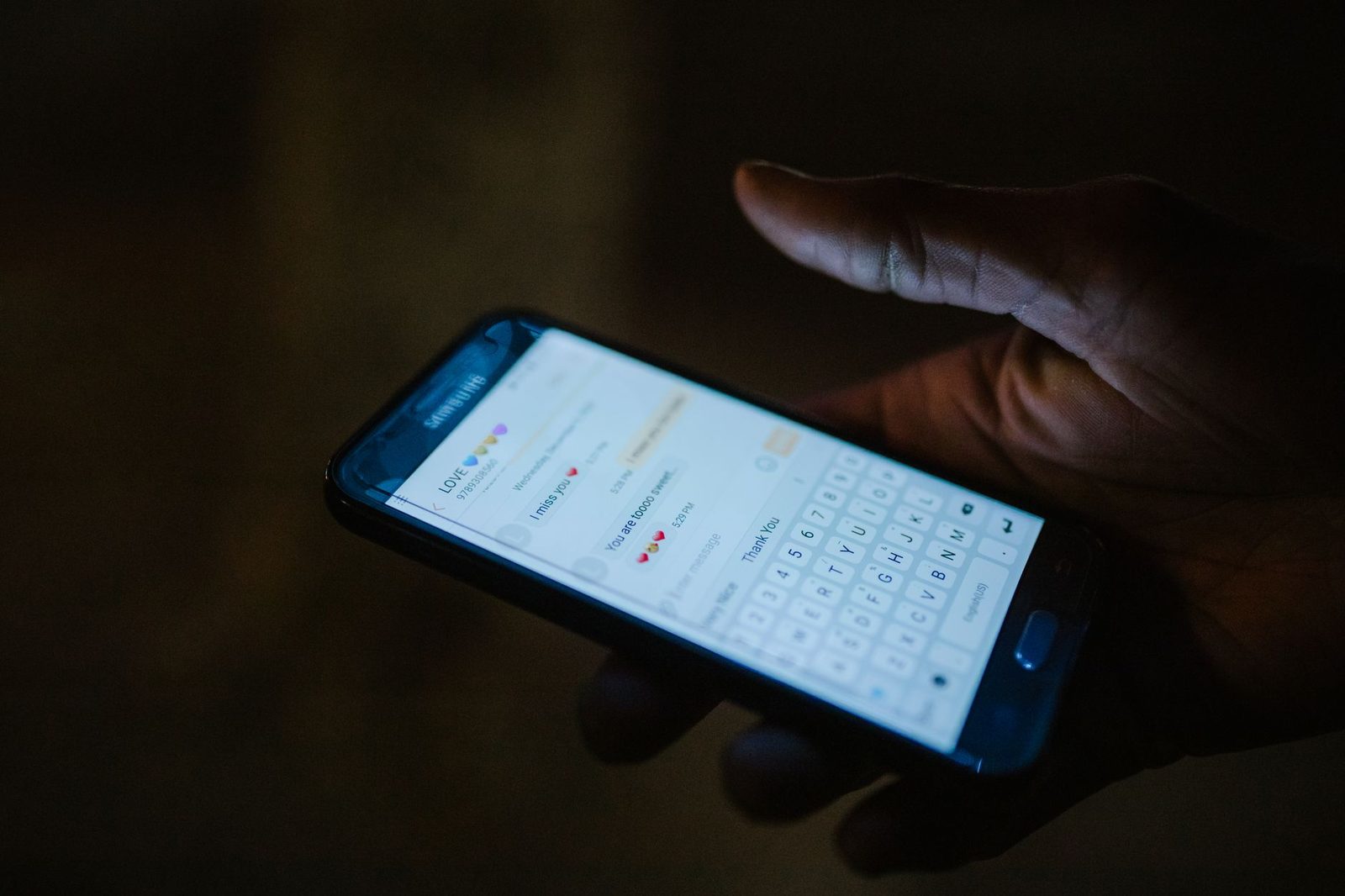 Mão segurando smartphone com aplicativo de mensagens iluminado, simbolizando atendimento noturno