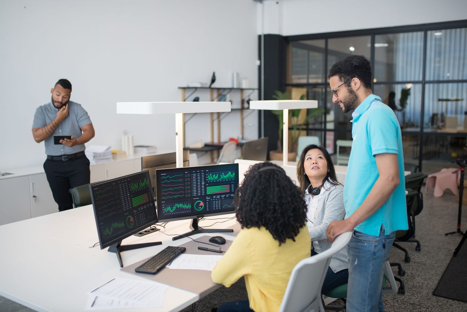 Equipe colaborando em escritório moderno com laptops, representando produtividade no trabalho com ferramentas de IA