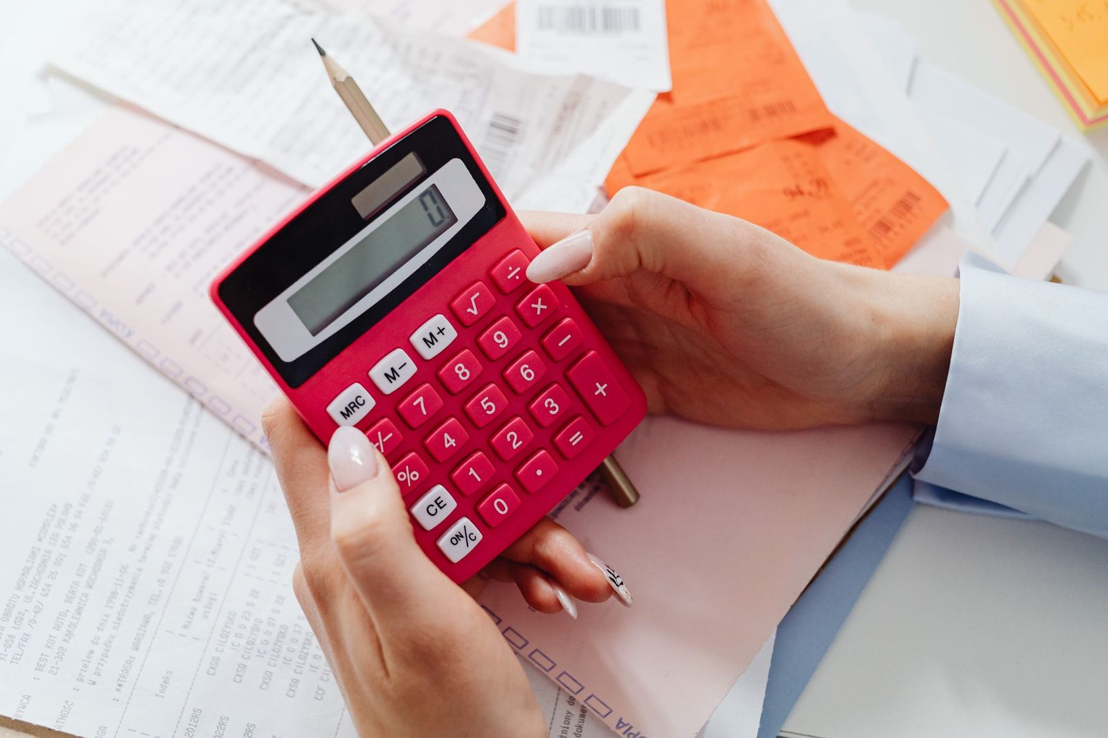 Mãos segurando uma calculadora sobre documentos financeiros