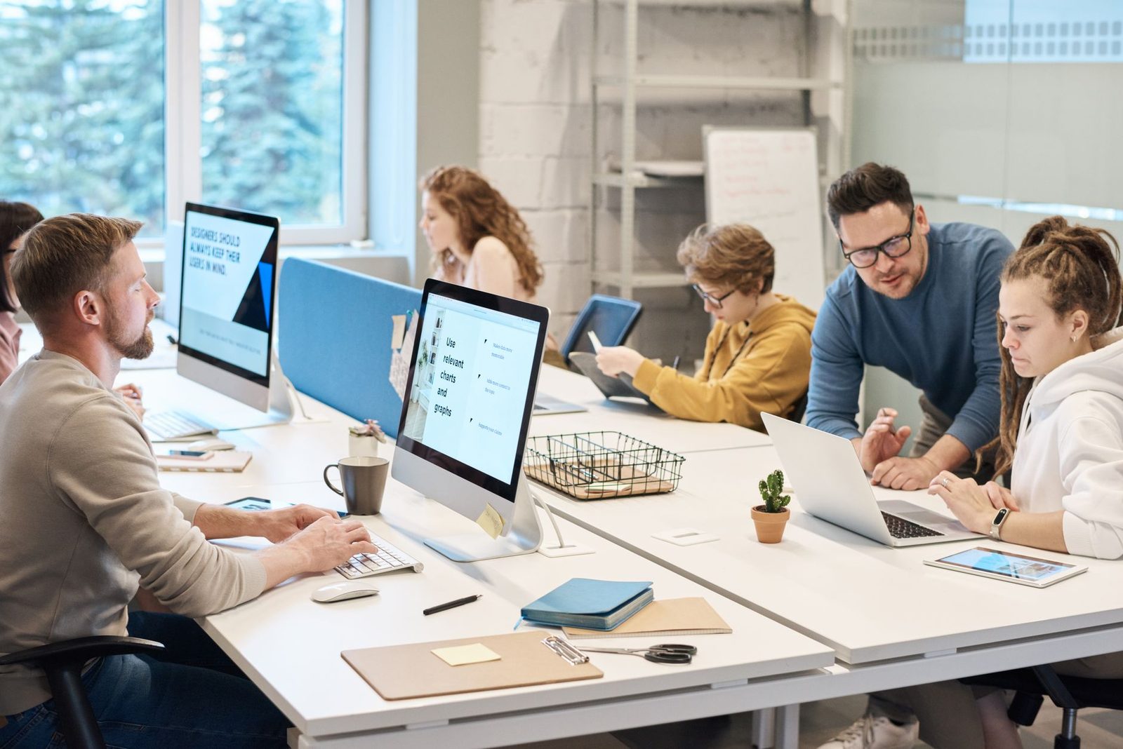 Equipe colaborando em ambiente de escritório moderno usando computadores e tecnologia