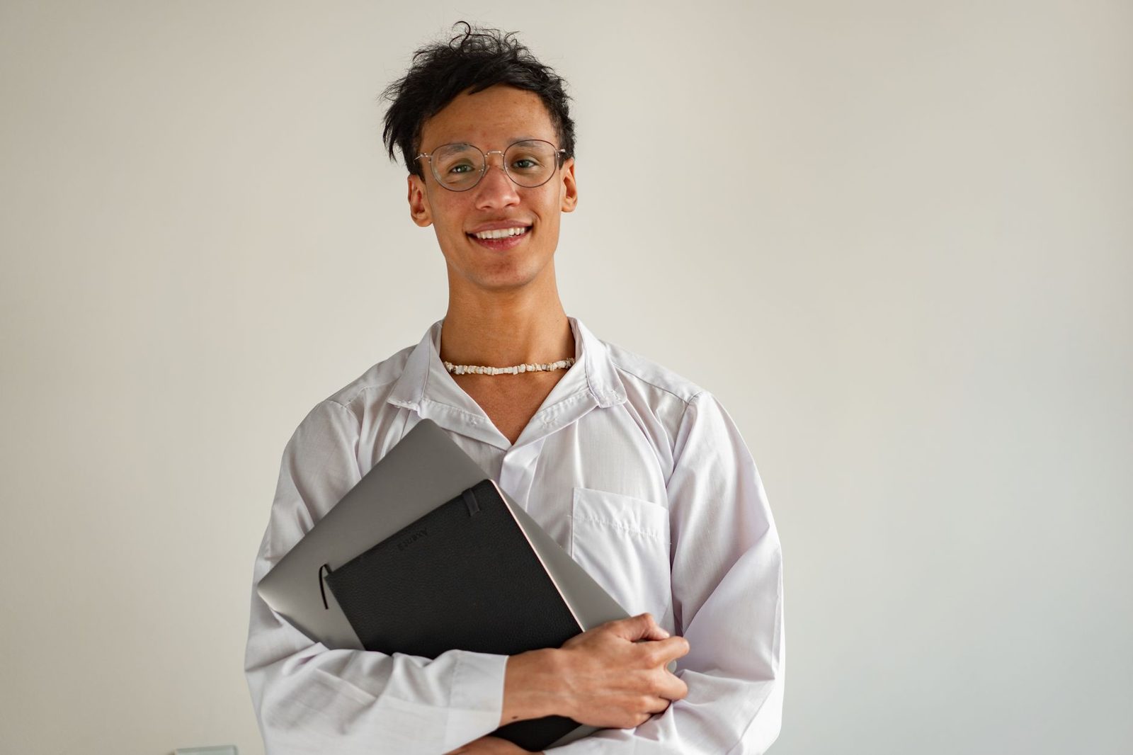 Pessoa jovem segurando notebook e caderno com expressão confiante, representando preparação e aprendizado ativo diante da IA